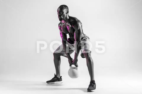 Young african-american bodybuilder training over grey background Stock Photos