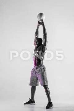 Young african-american bodybuilder training over grey background Stock Photos