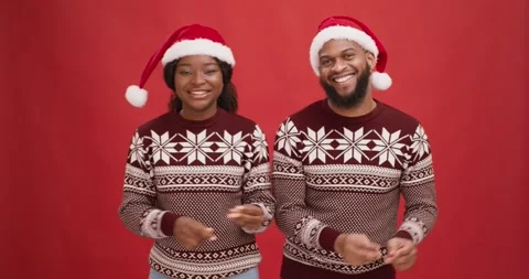 Young african american couple wearing sweaters and santa hats dancing and