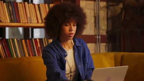 Young African American developer typing on laptop in a coffee shop, freelance Stock Footage 315667001