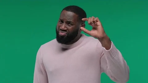 Young african american guy gesturing with hand doing small size sign with Stock Footage 155354373
