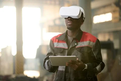 Young African American machine operator in vr headset using tablet Stock Photos