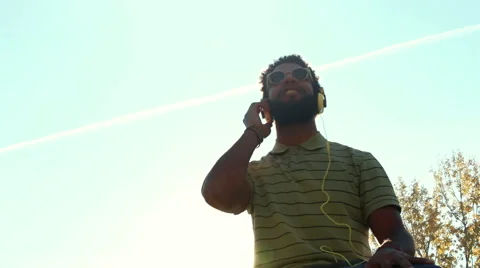 Young african american man with headphones listening to music at park Stock Footage 59555387