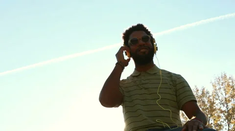 Young african american man with headphones listening to music at park Stock Footage 59555397