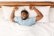 Young African-American Man Sleeping In Bed Top View Stock Photos