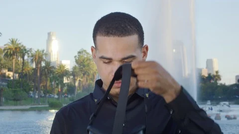 Young african american man using VR glasses by a fountain at a park Stock Footage 119335804