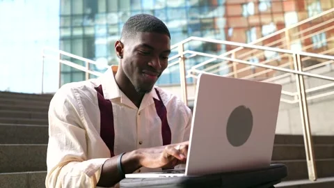 Young african american man using laptop on city steps Stock Footage 329164318