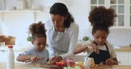 Young African American Mom Teaching Little Kids Cutting Fresh Vegetables. Stock Footage