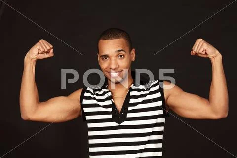 Young african-american muscular man in striped t-shirt on dark background Stock Photos