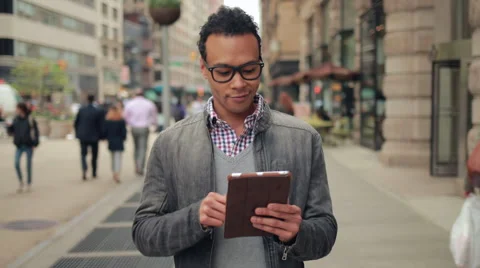 Young African Asian man in city walking using tablet pc computer Stock Footage
