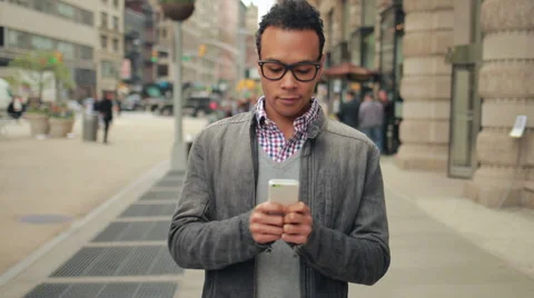 Young African Asian man in city walking texting cell phone Stock Footage