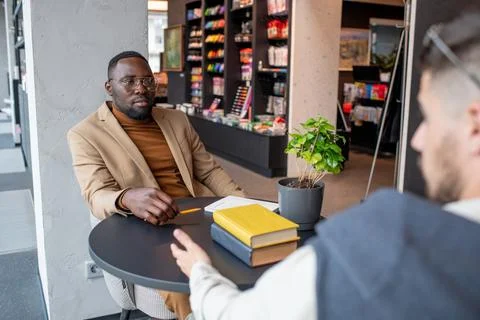 Young African businessman looking at colleague during interaction Stock Photos