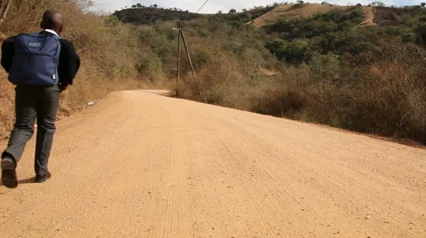 Young African child walking to school along winding rural dirt road Stock Footage 48295115