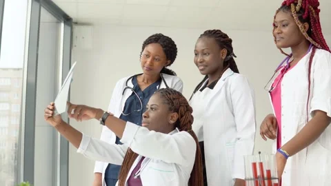 Young african doctors examine an X-ray while standing at a table Stock Footage 148238997