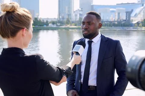 Young African entrepreneur standing in front of female reporter or journalist Stock Photos