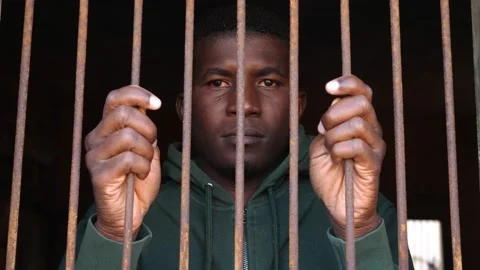 Young african grabs bars staring at the camera with anguished look Stock Footage 224284474