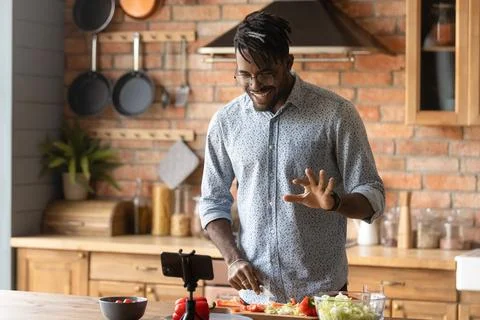 Young african guy broadcast live preparing dish on domestic kitchen Stock Photos