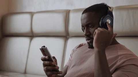 Young african guy is picking up a good phine, listening to music in his headset Stock Footage 86894538