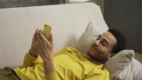 Young African Lying on the Couch Using a Smartphone Stock-Footage 164779417
