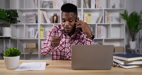 Young african man designer talking with client at distance by mobile phone  Stockbeeldmateriaal 200859922