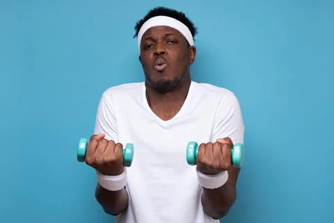 Young african man doing exercise with dumbbells spend time in gym. Stock Photos