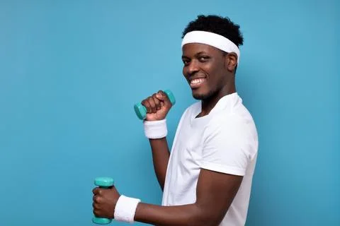 Young african man doing exercise with dumbbells spend time in gym. Stock Photos
