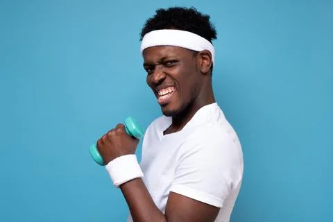 Young african man doing exercise with dumbbells spend time in gym. Stock Photos