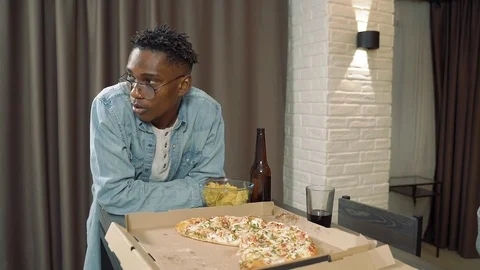 Young african man drinking beer and eating chips while meeting friends Stock Footage 122690708