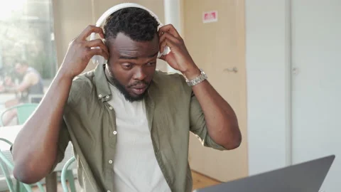 Young African man picking up computer and music headphones after working. 스톡 동영상 162333272