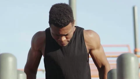 Young african man is pulling up on horizontal bar in city park. Stock Footage 143501518