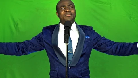 Young african man singing over green background and looking at camera. 스톡 동영상 74877955