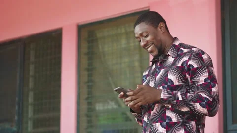 Young African Man Smiling Using Smartphone at home. Chats with family online. Stock Footage 345522866