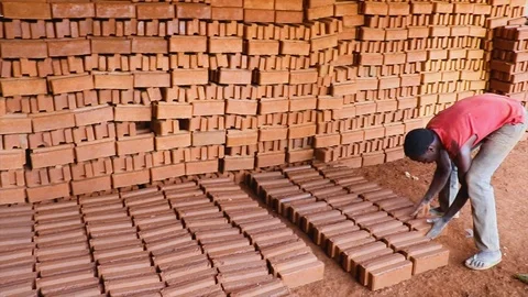 A young African man stacking and storing mud bricks in rural Africa. Stock Footage 114656475
