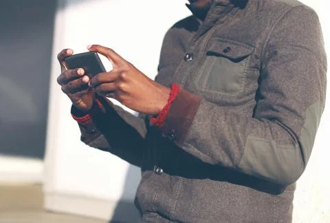 Young african man is using a smartphone in the city, closeup hands Stock Photos