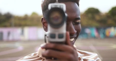 Young african man using vintage old video camera outdoor Stock Footage 185514593
