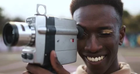 Young african man using vintage old video camera outdoor Stock Footage 185514600