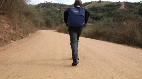 Young African scholar walking to school along winding rural dirt road Stock Footage 48302085
