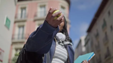 Young african student offering green apple on city street to the camera Stock Footage 307019149