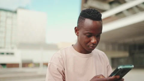Young african student sitting outside of university, using cellphone, sending Stock Footage 226930690