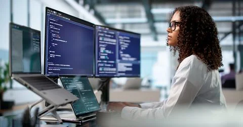 Young African Woman Engineer Coding On Laptop And Desktop At Busy Desk Stock Photos