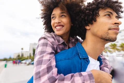 Young afro african american couple piggybacking while spending leisure time Stock Photos