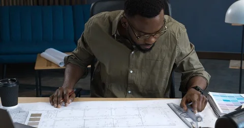 Young afro-American Engineer makes engineering ruler Measurements on Blueprints Stock Footage 126235217