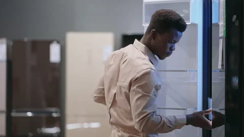 Young afro-american guy is choosing new refrigerator in home appliance store Stock Footage 153072478