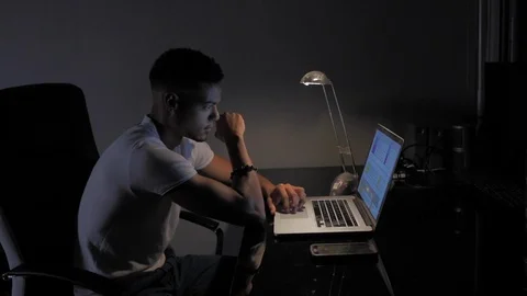 Young afro american man working on computer with bedside lamp at night in his Video stock 110772205