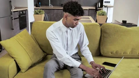 Young afro man freelancer using laptop device on cozy couch at home Stock Footage 142634034