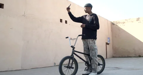 Young afro man rapper making a selfie with his trials bike in the street.Youn Stock Footage 151484484