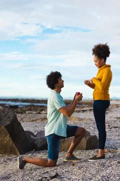 Young afro man with ring box proposing african american girlfriend while Fotos Stock