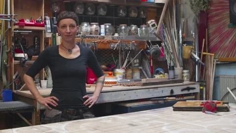 Young alternative female carpenter posing for the camera in her workshop, slow Stock Footage 134473386