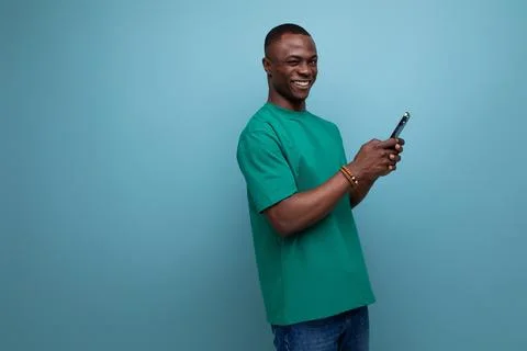 A young american guy dressed in a basic t-shirt writes a message on the phone on Stock Photos