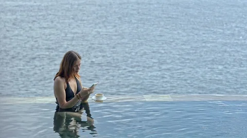 Young american woman using smartphone resting in ocean pool on bali island. Vídeo Stock 123090153